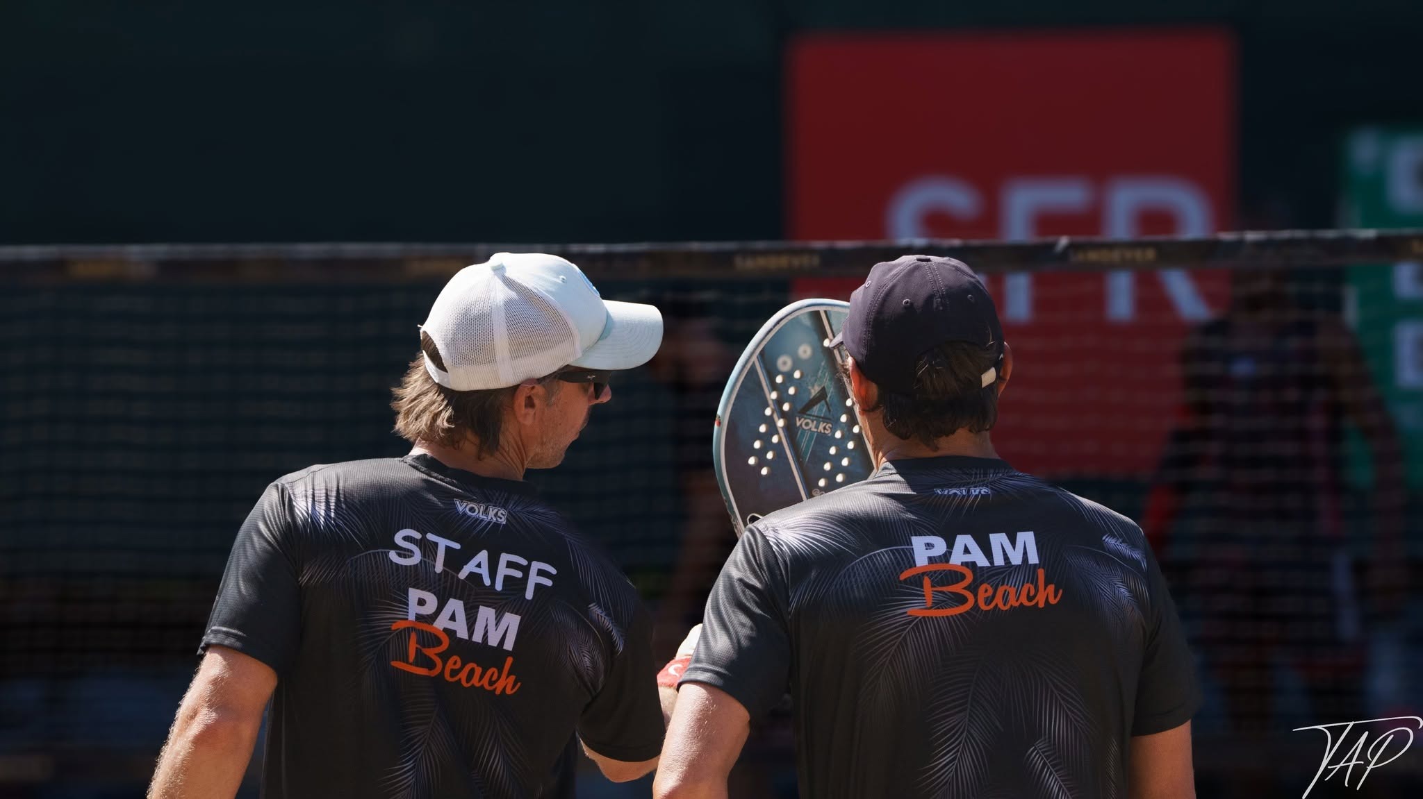 Cédric Dupuy échange avec un joueur sur un terrain de Beach Tennis